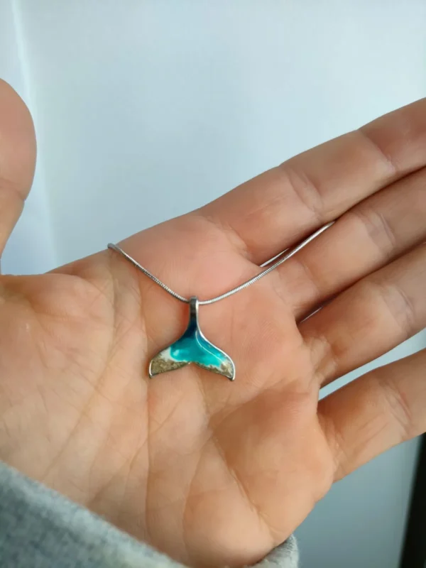 Colgante de cola de ballena de resina sobre la palma de una mano