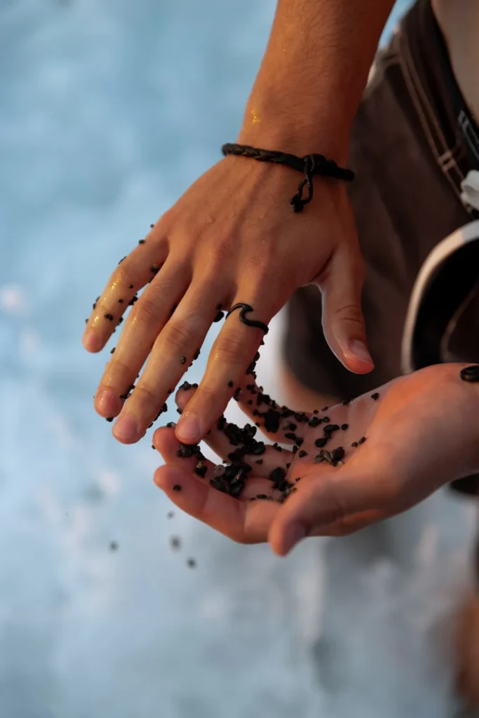 Manos con pulseras Sea Jeys dejando caer arena negra