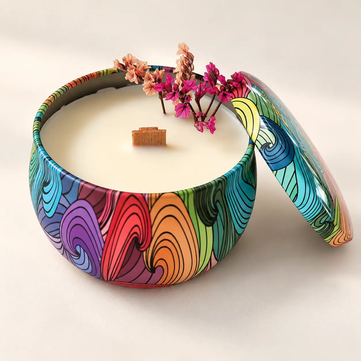 Vela en lata de colores con la tapa abierta, mecha de madera y flores preservadas