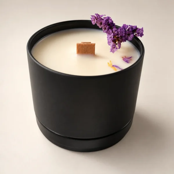 Vela en lata negra con mecha de madera y flores moradas